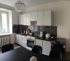 a kitchen with white cabinets and a table with chairs at Cozy Central City Apartment in Ulaanbaatar