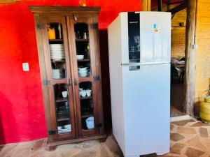 a white refrigerator next to a cabinet with dishes at Rancho encontro dos sonhos in Carrancas