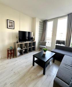 Una sala de estar con un sofá y un televisor. en Appart ensoleillé à Boulogne Billancourt, en Boulogne-Billancourt