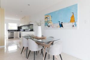 Un comedor con una mesa de cristal y sillas blancas. en Sunset Sands on Esplanade By Host Solutions, en West Beach