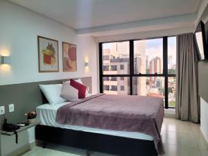 a bedroom with a bed and a large window at Suíte no Manaíra Apart Hotel in João Pessoa +22 photos