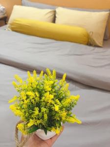 a person holding a bouquet of yellow flowers on a bed at Na Tuệ An-Homestay Số 3 Hoàng Văn Thái in Tuyên Quang