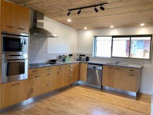 a kitchen with wooden cabinets and stainless steel appliances at The Nutshed in Matata