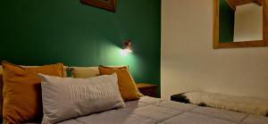 a bedroom with a bed with pillows and a green wall at Hospedaje Mi Rincón El Chaltén in El Chalten