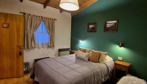 a bedroom with a bed with a green wall at Hospedaje Mi Rincón El Chaltén in El Chalten