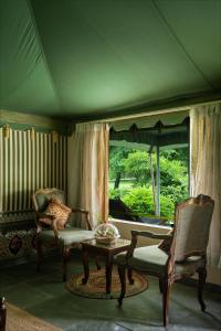 a living room with chairs and a table and a window at Kutani Bagh Sariska in Tehla