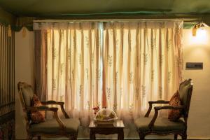 two chairs and a table in front of a window at Kutani Bagh Sariska in Tehla +41 photos