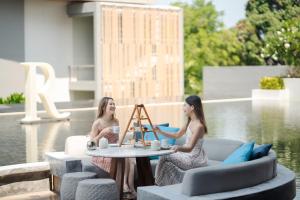 two women sitting around a table on a patio at Renaissance Pattaya Resort & Spa in Na Jomtien