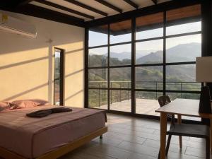 a bedroom with a bed and a desk and a large window at Villa Cerat Escapada de lujo cerca de Medellin-Pets friendly in Sopetrán