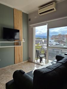 a living room with a couch and a tv and a balcony at Departamentos Güemes in San Fernando del Valle de Catamarca +91 photos