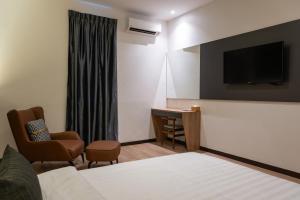 a hotel room with a bed and a desk and a tv at Blu Sentral Hotel in Tawau