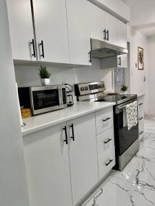Una cocina blanca con gabinetes blancos y un microondas. en K2 Room Near Airport, en Mississauga