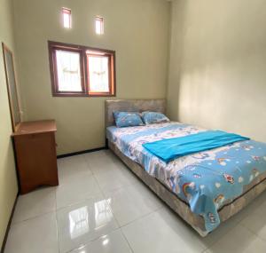 a bedroom with a bed with blue sheets and a window at Ijen kingdom guest house in Tamansuruh