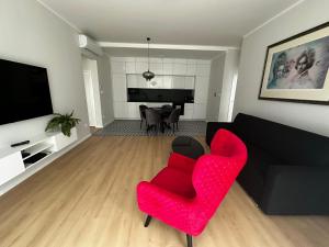 a living room with a red chair and a black couch at Apartmán Beethoven in Turčianske Teplice