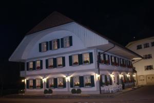 um grande edifício branco com mesas e cadeiras à noite em Gasthof Löwen em Melchnau