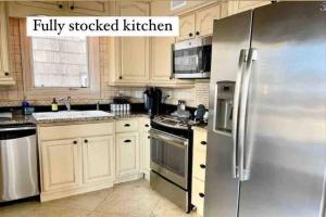 eine Küche mit weißen Schränken und einem Edelstahlkühlschrank in der Unterkunft Be A Nomad - Oceanviews Bottom and Steps to the Beach in Jacksonville Beach