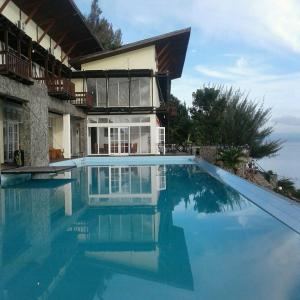 a large swimming pool in front of a house at Tiara Bunga Hotel & Villa in Balige