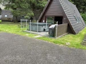 a house with a deck with a grill and a table at Bright Star Lodge in Spean Bridge
