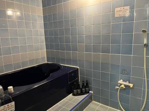a bathroom with a shower with blue tiled walls at adult only ホテルシャルム in Itoigawa
