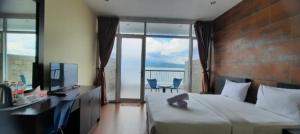 a bedroom with a bed and a desk with a view at Tiara Bunga Hotel & Villa in Balige