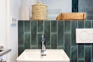 a white sink in a bathroom with green tiles at Buhne 44 in List +46 photos