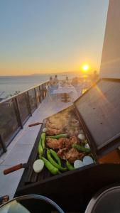 a grill with meat and vegetables on a balcony with the sunset at Ugem in Seferihisar