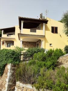 una casa gialla con un muro di pietra di fronte di Appartamenti I Mandorli a Budoni
