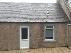 a brick house with a white door and windows at 7 High Buckholmside in Galashiels