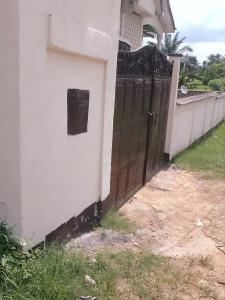 Una valla blanca con una puerta negra al lado de una casa. en LIKARLELoc, en Edéa