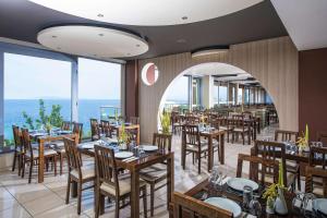 een restaurant met tafels en stoelen met de oceaan op de achtergrond bij Blue Bay Resort Hotel in Agia Pelagia