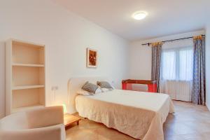 a bedroom with a bed and a chair and a window at Quic in Playa de Muro