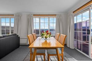 サンディ・ベイにあるLuxury Sandy Bay Living River Views Free Parkingのテーブルと椅子と窓のあるダイニングルーム