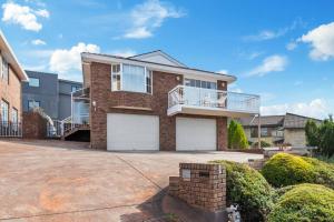 サンディ・ベイにあるLuxury Sandy Bay Living River Views Free Parkingの白いガレージドアが2つあるレンガ造りの家