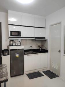 a kitchen with white cabinets and a stainless steel refrigerator at Dorothy's Door Condo in Bacolod
