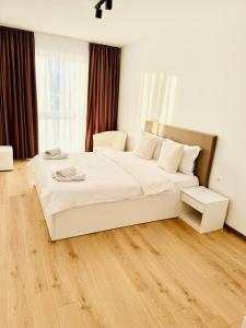 a bedroom with a white bed and a wooden floor at Milan Luxury Apartaments VI-Maurer Residence in Târgu-Mureş