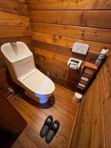 a bathroom with a toilet in a wooden wall at Hakuba Brownie Cottages in Hakuba
