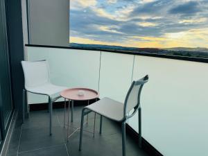 a balcony with two chairs and a table and a window at Milan Luxury Apartaments VI-Maurer Residence in Târgu-Mureş