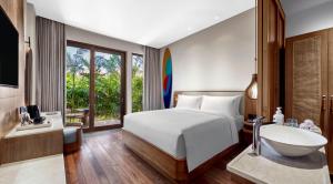 a bedroom with a bed and a sink and a tub at Holiday Inn Resort Bali Canggu by IHG in Canggu