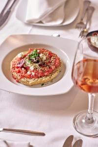 a plate of pizza on a table with a glass of wine at Blue Sea Beach Resort in Faliraki