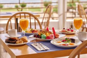 a table with plates of food and two glasses of orange juice at Blue Sea Beach Resort in Faliraki
