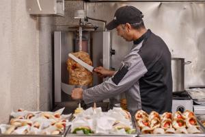 a man is preparing food in a kitchen at Blue Sea Beach Resort in Faliraki