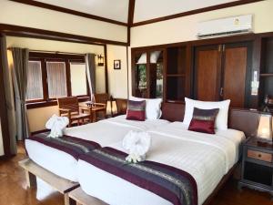 two beds in a hotel room with white sheets and red pillows at Koh Mook Sivalai Beach Resort in Ko Mook