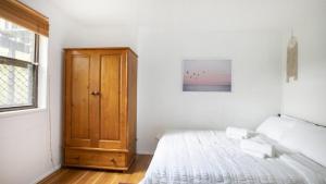 - une chambre blanche avec un lit et une armoire en bois dans l'établissement Copacabana Tranquil Escape Views, Pet Friendly On Request Accom Holidays, à Copacabana