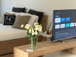 パッソスクロにあるLuxury Apartments Collection Sand Suiteのテレビの隣のテーブルに置かれた花瓶の花