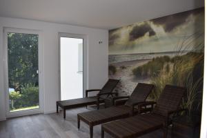 a room with chairs and a painting of a beach at Sellinkoje in Ostseebad Sellin