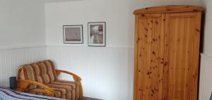 Bungalow Rose في لودين: غرفة نوم مع كرسي وخزانة خشبية