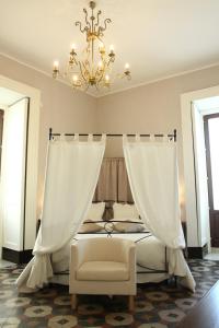 a bedroom with a bed with a chandelier and a chair at B&B Suite Cutelli in Catania