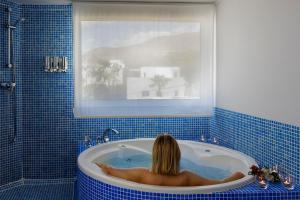 a woman in a bath tub in a blue tiled bathroom at miKasa Agua Amarga & SPA in Agua Amarga