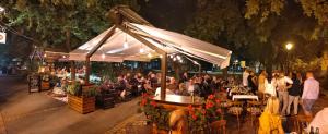 un gruppo di persone seduti ai tavoli sotto una tenda di Restoran Orijent 5 a Sombor