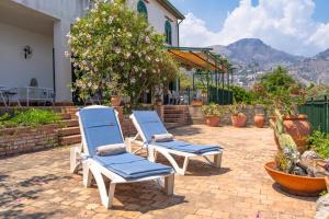 陶尔米纳La casa di Angelo的两把蓝色椅子放在带房子的庭院